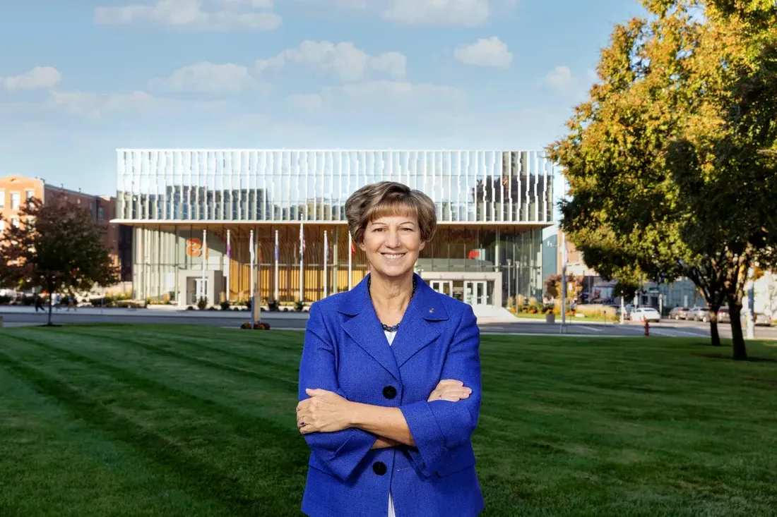 Portrait of Eileen Collins standing with a view of the National Veterans Resource Building.